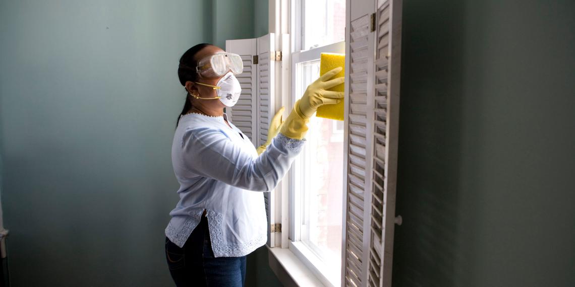 Woman in protective gear cleaning a window frame