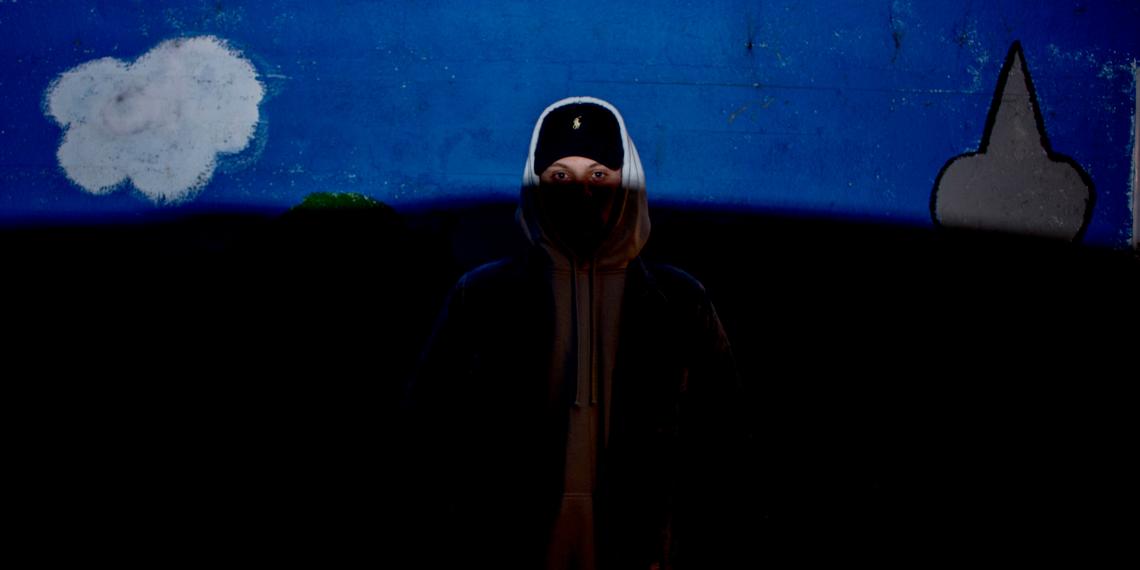 Youth wearing a hoodie half in shadows
